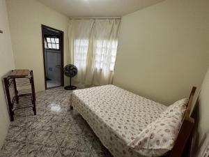 1 dormitorio con 1 cama y ventana con ventilador en 3 Quartos ótimo custo benefício Angra Garatucaia, en Angra dos Reis