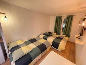 two beds in a small room with green curtains at T2D Apartment - Suite TVR proche Disneyland Paris in Bussy-Saint-Georges