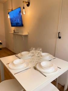 a table with white plates and wine glasses on it at T2D Apartment - Suite TVR proche Disneyland Paris in Bussy-Saint-Georges