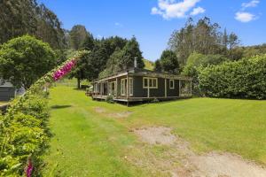 a green house in a field with a yard at Back of Beyond Cottage in Rotoiti