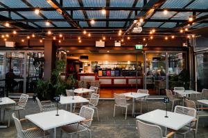 un restaurante con mesas blancas, sillas y luces en Clarendon Hotel, en Newcastle