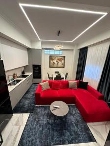 uma sala de estar com um sofá vermelho e uma cozinha em Skyen Luxury Apartments em Durrës