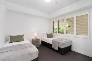 2 camas en una habitación blanca con ventana en Las Rias Holiday Apartments, en Noosa Heads