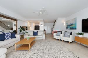 una sala de estar con sofás blancos y una mesa. en Las Rias Holiday Apartments, en Noosa Heads
