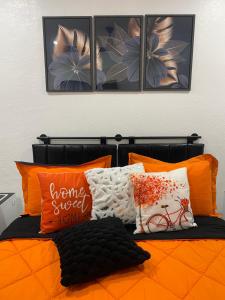 1 dormitorio con 1 cama naranja y 4 cuadros en la pared en Magnolias Suite en Lehigh Acres