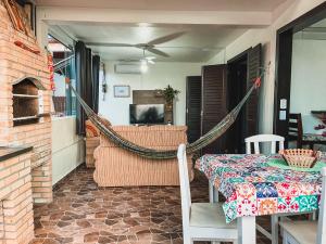 a porch with a hammock and a table and a television at Casa 3 - Estrela Dalva, vista para o mar! in Farol de Santa Marta