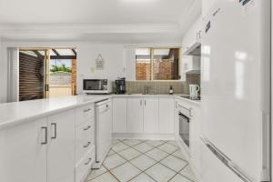 a white kitchen with white cabinets and appliances at Shells by Experience Jervis Bay in Huskisson
