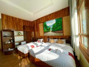 um quarto com duas camas e um quadro na parede em Kum-Chan House Hotel (เฮือนก่ำจันทร์) em Nan