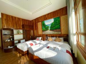 a bedroom with two beds and a painting on the wall at Kum-Chan House Hotel (เฮือนก่ำจันทร์) in Nan