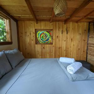 Cama blanca grande en habitación de madera con ventana en Cabana del Rio Lejos Pijao, Finca Flora del Rio en Pijao