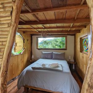 a bed in a log cabin with a window at Cabana del Rio Lejos Pijao, Finca Flora del Rio in Pijao