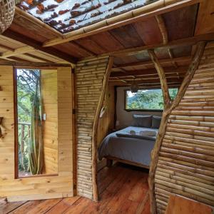 una camera da letto in una baita di tronchi con un letto in esso di Cabana del Rio Lejos Pijao, Finca Flora del Rio a Pijao