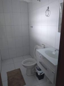 a white bathroom with a toilet and a sink at Casa térrea com piscina e aconchegante perto da praia in Itanhaém