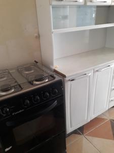 cocina con fogones negros y armarios blancos en Porto apartamento 6, en Porto Seguro