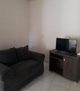 sala de estar con sofá negro y TV de pantalla plana en Porto apartamento 6, en Porto Seguro