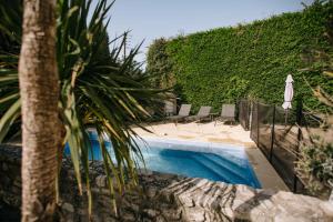 una piscina con sillas y un seto en Charming villa in the heart of the watershed, en LʼIsle-sur-la-Sorgue