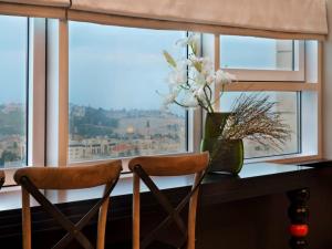 una finestra con due sedie e un vaso di fiori di 21st Floor Hotel a Gerusalemme