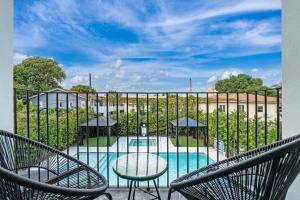 a balcony with chairs and a pool with a fence at Lux Retreat By Renzzi in Miami