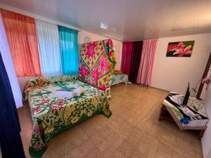 Habitación con silla y cama con cortinas coloridas. en Toamanahere Guesthouse en Tubuai