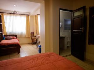 1 dormitorio con 1 cama y puerta al baño en Refugio del Turista, en Tupiza