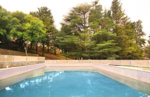 una piscina de agua azul con árboles en el fondo en El Pinar en Bialet Massé