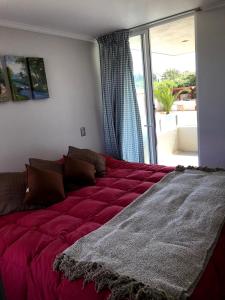1 cama grande de color rojo en una habitación con ventana en Apartment La Serena Pacifico, en La Serena