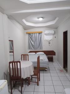 a room with two beds and a table and chairs at HOTEL NEW´S BUSINESS in Macapá