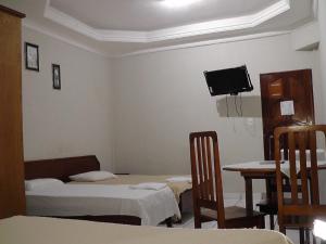 a room with two beds and a table and a tv at HOTEL NEW´S BUSINESS in Macapá