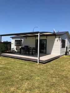 a small white house with a porch and a table at Whitianga Kiwi Bach in Whitianga