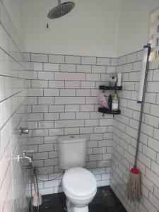 La salle de bains est pourvue de carrelage blanc et de toilettes. dans l'établissement DRS Legacy Homestay, à Kamunting