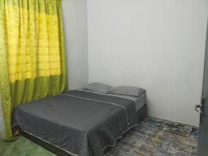 - une petite chambre avec un lit et un rideau jaune dans l'établissement Homestay Sri Awana, à Alor Setar