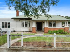 uma casa branca com uma cerca à frente. em Piper St Cottage em Yarrawonga