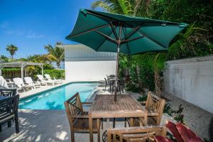 a wooden table with an umbrella next to a pool at Bayside Cutie at Bayside Bungalow in Anna Maria