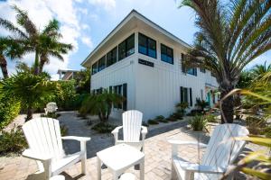 a group of white chairs in front of a house at Bayside Cutie at Bayside Bungalow in Anna Maria
