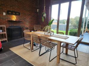 uma mesa e cadeiras num quarto com uma parede de tijolos em Hillcrest Harmony: Luxury in Westmeadows 20% OFF em Melbourne