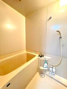 een badkamer met een bad, een douche en een wastafel bij Ueda Building - Vacation STAY 13581 in Asahikawa