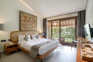 Kandarpa Ubud CHSE Certified في أوبود: غرفة نوم بسرير ومكتب ونافذة