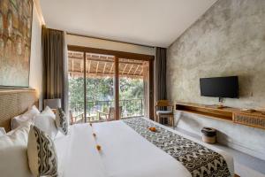 a bedroom with a large white bed and a tv at Kandarpa Ubud CHSE Certified in Ubud