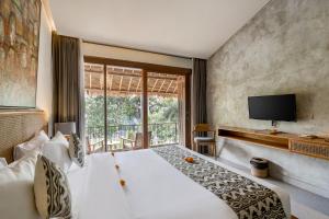 Kandarpa Ubud CHSE Certified في أوبود: غرفة نوم بسرير ابيض كبير وتلفزيون