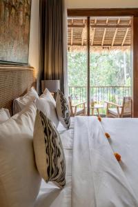 a bedroom with a bed with white pillows and a window at Kandarpa Ubud CHSE Certified in Ubud
