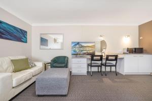 a living room with a couch and a table and chairs at Elizabeth Motor Inn in Newcastle