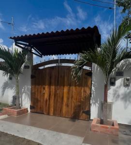 a wooden gate to a house with two palm trees at Loft Moderno in Mariquita