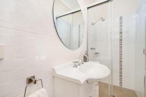 ein weißes Badezimmer mit einem Waschbecken und einem Spiegel in der Unterkunft Elizabeth Motor Inn in Newcastle