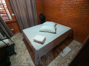 1 dormitorio con cama y pared de ladrillo en Residencial Colling en Canela