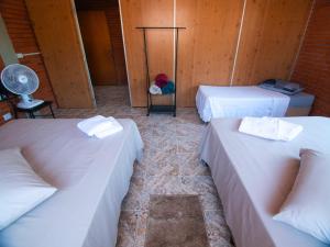a room with three beds and a fan at Residencial Colling in Canela
