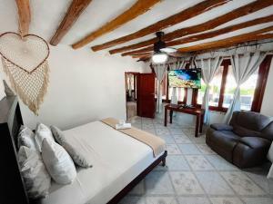 a bedroom with a bed and a couch and a tv at Casa Playa Holbox! in Holbox Island +31 photos