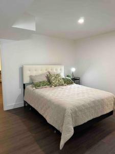 een slaapkamer met een groot bed met een witte muur bij Oakville's Retreat in Oakville