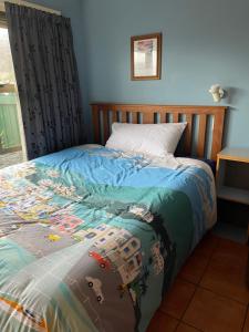 a bed with a colorful comforter on it at The Bug Backpackers in Nelson