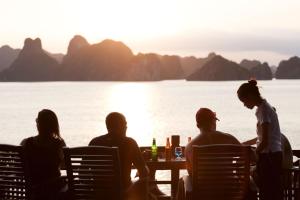 a group of people sitting at a table by the water at Mila Lux Cruises in Ha Long