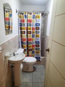 a bathroom with a toilet and a shower curtain at Hospedaje Kaihalulu in Punta Hermosa